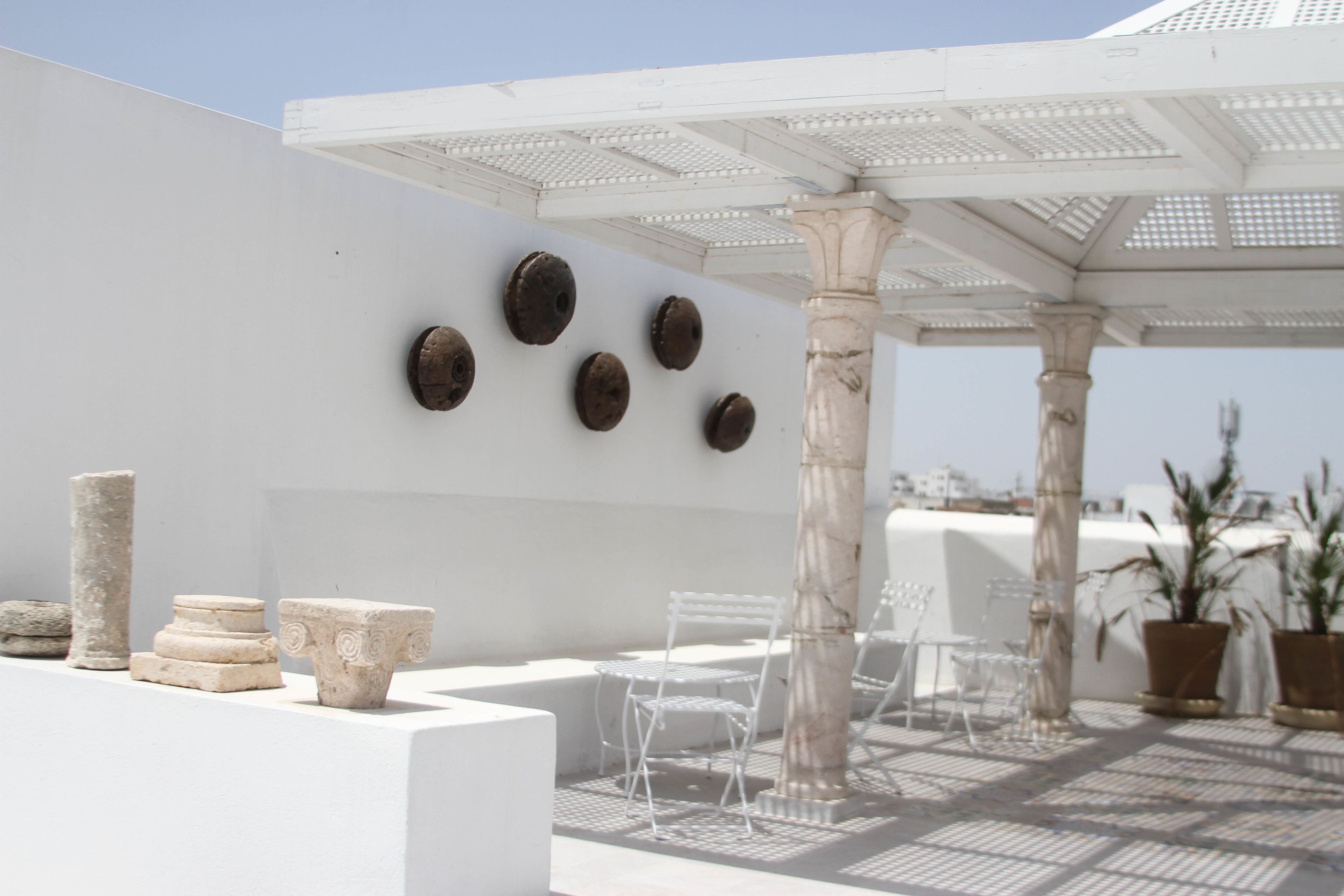 Une terrasse sur le toit agrémentée de colonnes blanches, d’une pergola et de sièges d’extérieur.