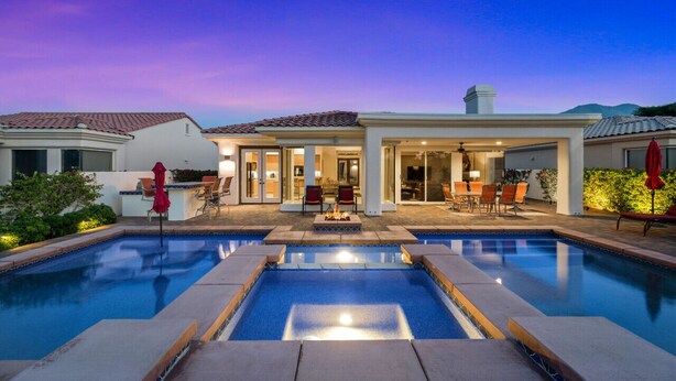 A modern house with a swimming pool, outdoor seating, and a patio area.