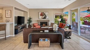 A spacious living room with a fireplace, comfortable seating, and a television.