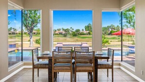 A dining area with a view of a pool and a golf course.