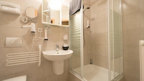 A modern bathroom with a glass-enclosed shower, a sink, and a mirror. - Design Hotel Rangau (Langenzenn)