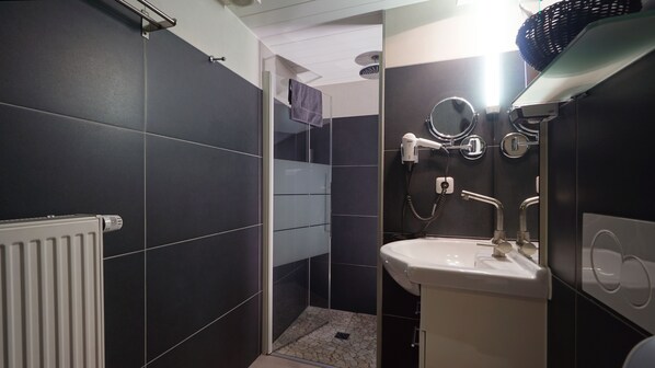 Une salle de bain moderne avec une douche à parois de verre, un lavabo blanc et un sèche-cheveux.