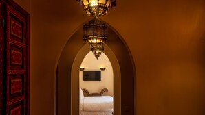 A hallway leading to a bedroom with a bed, a chandelier, and a TV on the wall. - Il Parco dei Principi (Marrakech)