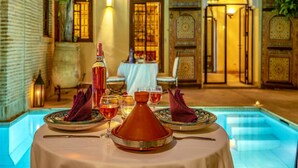 A dining table set with a bottle, glasses, and a traditional Moroccan tagine. - Il Parco dei Principi (Marrakech)