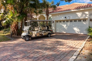 Une voiturette de golf est garée devant une maison qui a un garage.