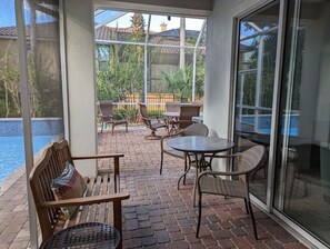 A covered patio with brick flooring, wicker furniture, and a view of a swimming pool. - Close2beach, private pool/spa/lanai, gym, theater, tennis&pickleball, playground (Destin)