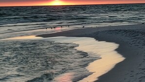 Una playa con olas y una puesta de sol.
