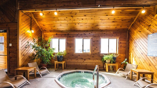A wooden cabin with a hot tub, seating, and potted plants. - Cozy 2 Bed, 2 Bath Condo on Golf Course with Hot tub, Sauna & Pool! (Red Lodge)