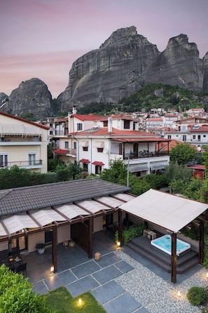 A residential area with stone buildings, a patio with a hot tub, and a view of mountains.
