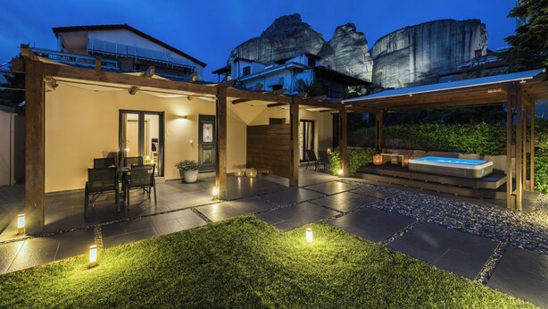 A modern outdoor patio area with a hot tub, seating, and a pergola structure. - Meteora boutique villa A (Kalampaka)