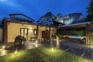 A modern outdoor patio area with a hot tub, seating, and a pergola structure. - Meteora boutique villa A (Kalampaka)