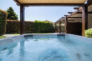 A hot tub under a pergola with a view of a hedge and a building in the background. - Meteora boutique villa A (Kalampaka)