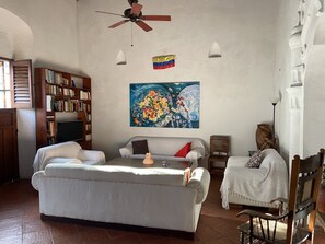 A living room with a sofa, a coffee table, a bookshelf, a painting, and a flag.
