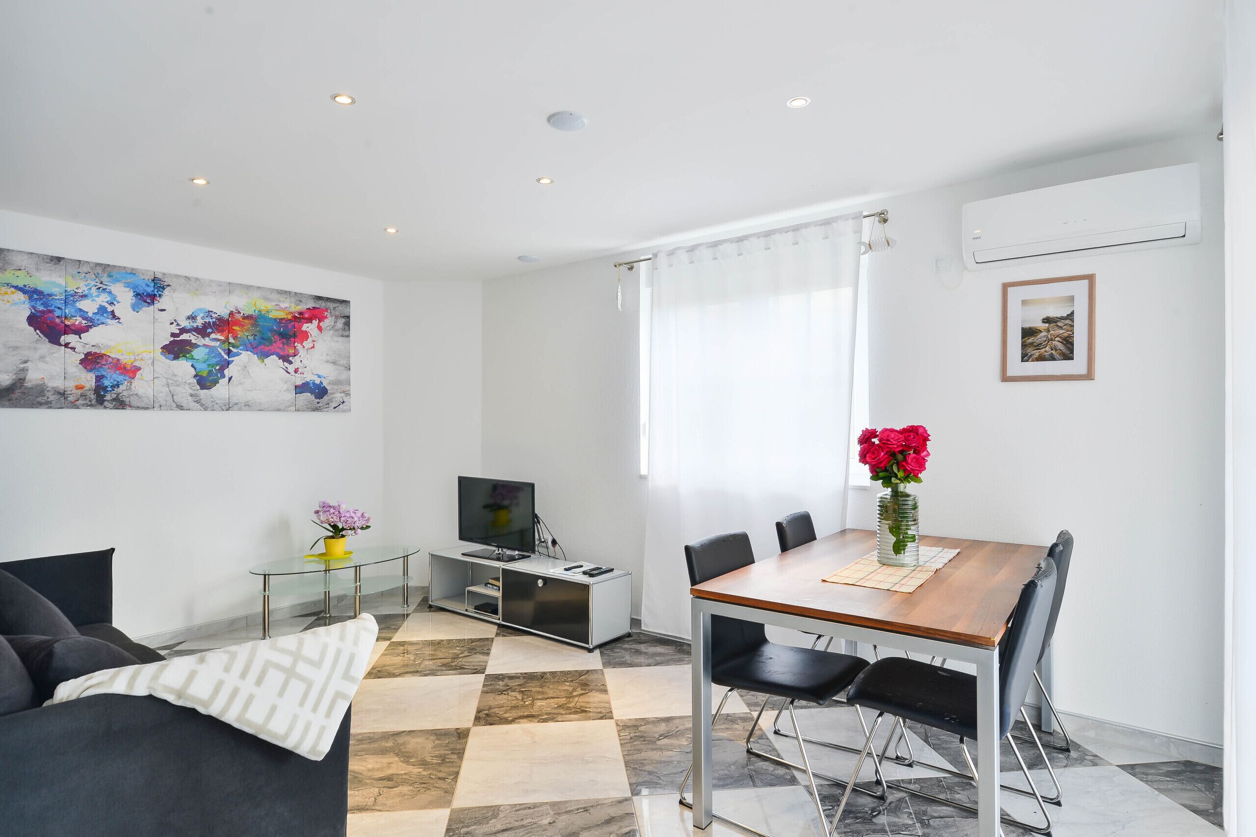 Una sala de estar moderna con un sofá, televisor y una mesa de comedor con sillas.