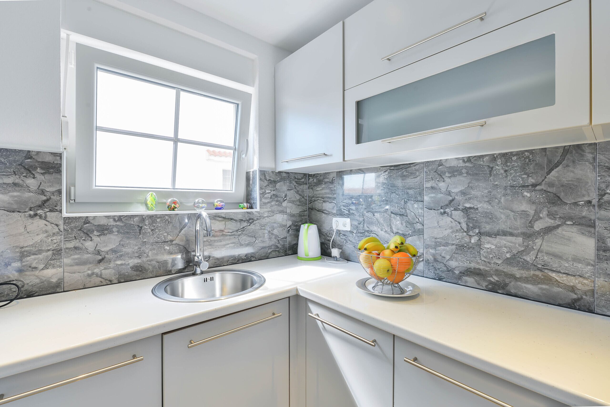 A modern kitchen with a sink, countertop, and a window.