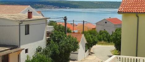 Un quartier résidentiel avec des maisons, une route asphaltée et une étendue d’eau en arrière-plan.