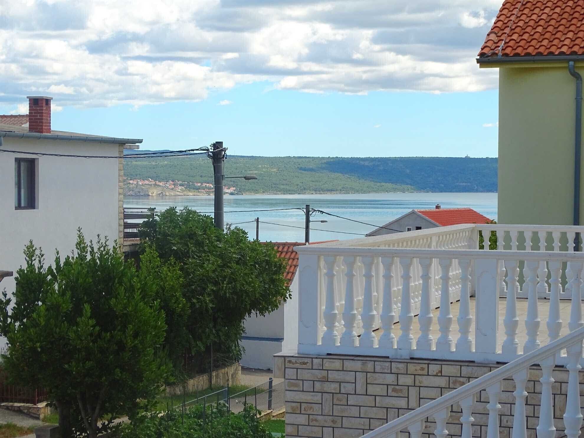 A residential area with a view of a body of water, a white building with a red roof, and a yellow building with a balcony.