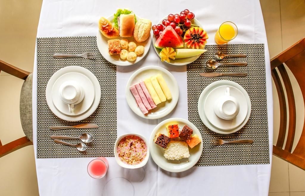 A breakfast setting with plates of food, utensils, and a beverage on a table.
