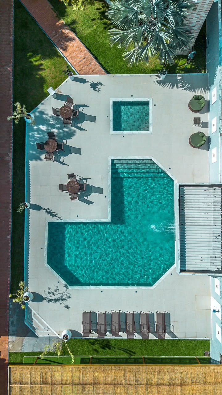 An aerial view of a swimming pool area with a sunken section, lounge chairs, and a small table.