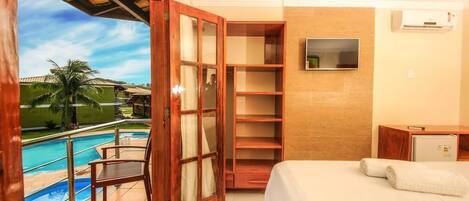 Habitación de hotel con cama, televisión, armario de madera y vista a una piscina.