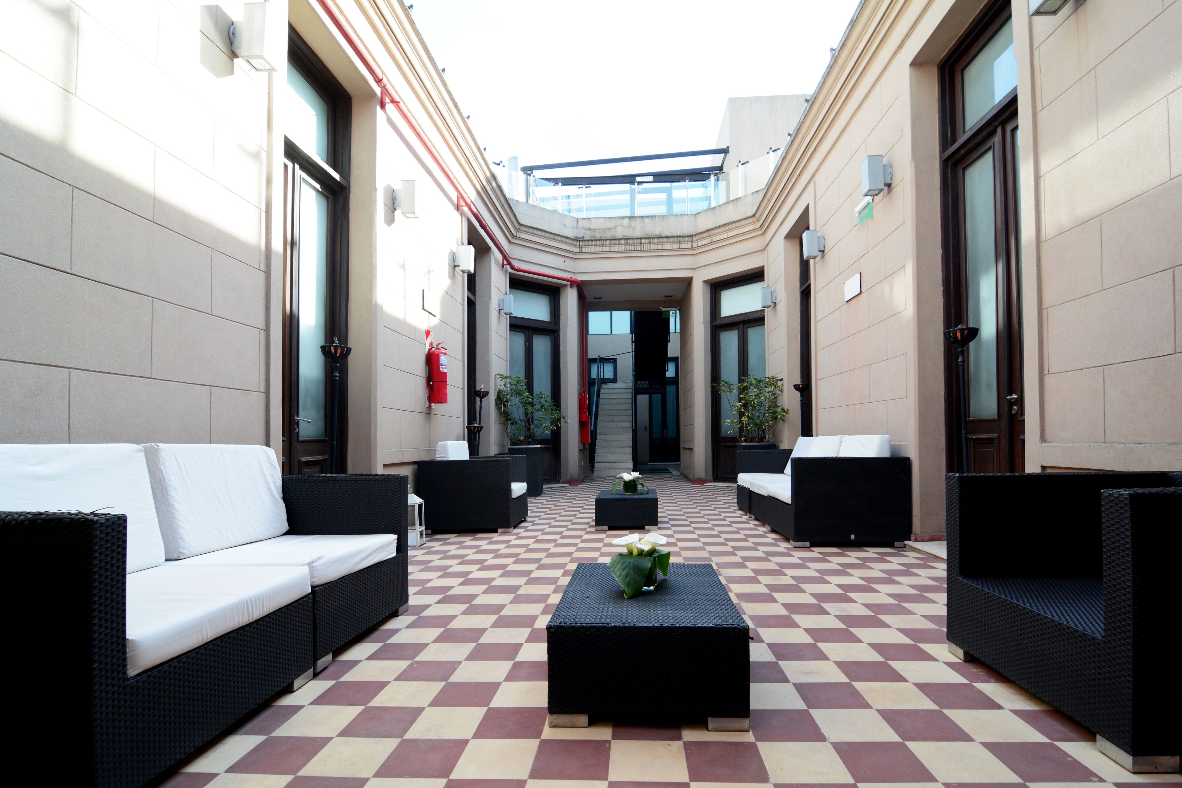 A courtyard with checkered flooring, outdoor seating, and a central table with plants.
