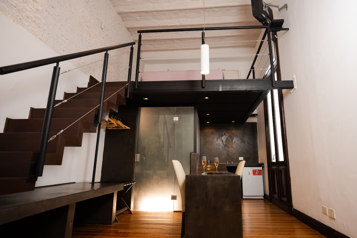 Un interior moderno con una escalera, un comedor con mesa y sillas, y una zona de cocina.