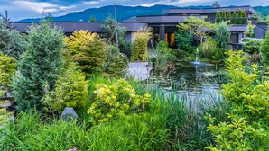 A modern building with a rooftop garden, a pond, and surrounding lush greenery. - The Lagoon Suite at The Estuary Inn (Nanoose Bay)