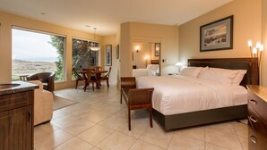 A hotel room with a large bed, a dining table, and chairs, a kitchen area, and a view of the outdoors. - The Lagoon Suite at The Estuary Inn (Nanoose Bay)