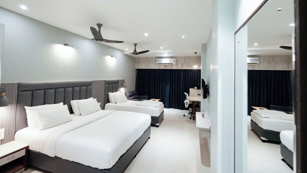 A hotel room with two beds, a desk, a chair, a mirror, and ceiling fans. - Hotel Lee Garden, Near Blue Flag Beach(500 Mtrs), Puri (Puri)