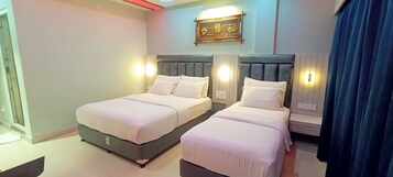 A hotel room with two beds, a wall-mounted light fixture, and a decorative sign.