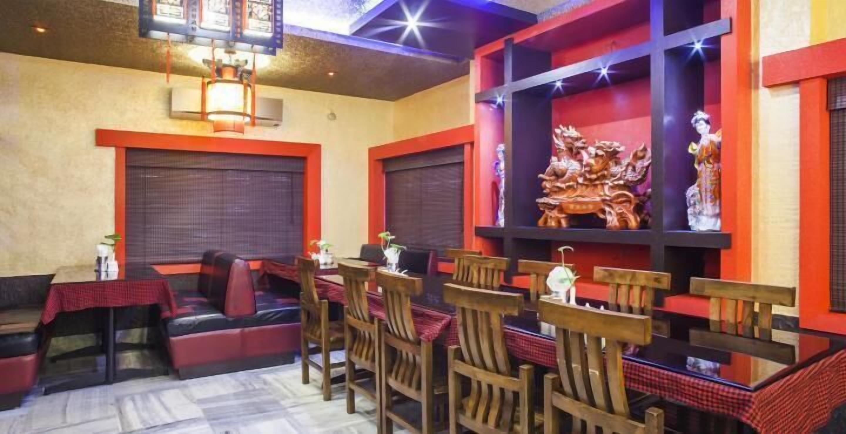 A restaurant with wooden chairs and tables, red cushions, and decorative wall art.