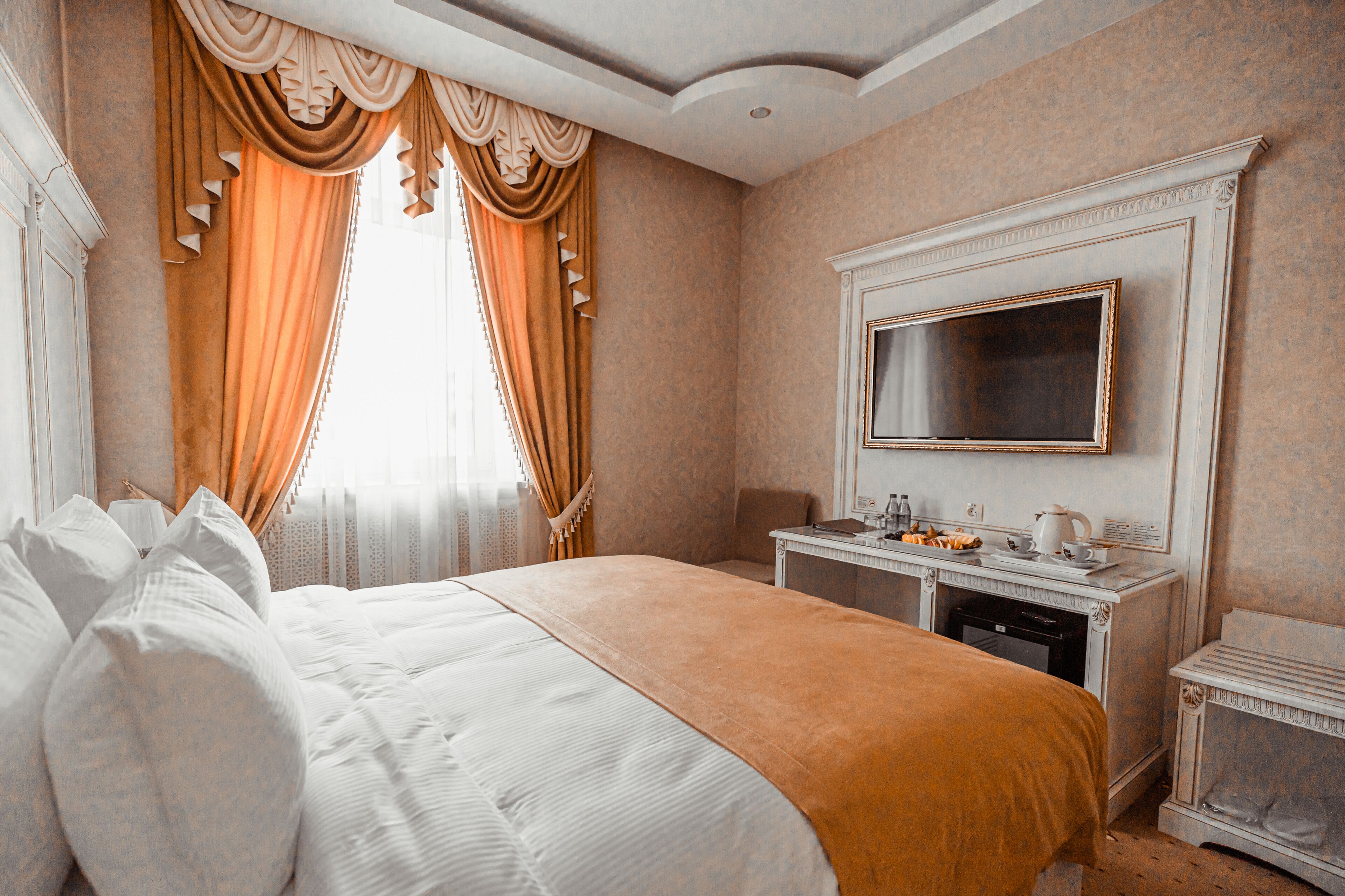 A hotel room with a large bed, a desk with a mirror, and a fireplace.
