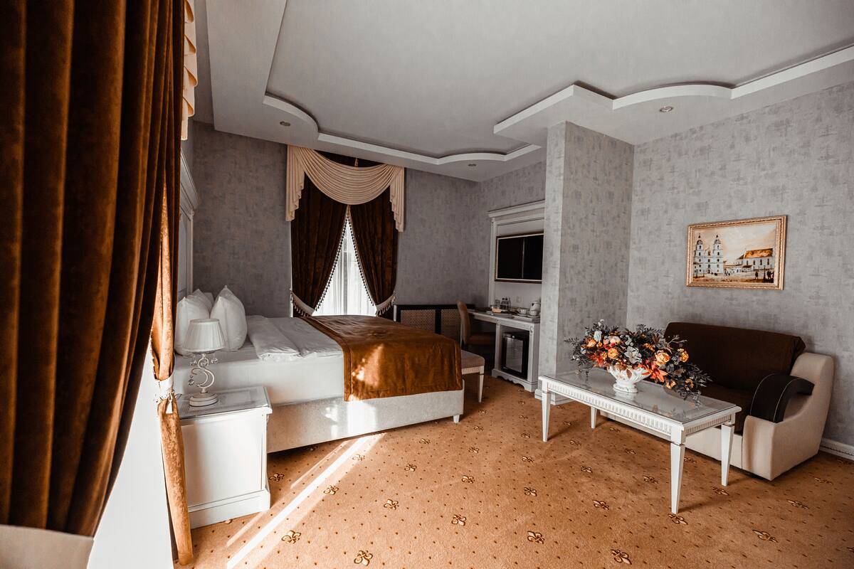 Une chambre d’hôtel avec un lit, un bureau, un canapé, une télévision et un tableau au mur.