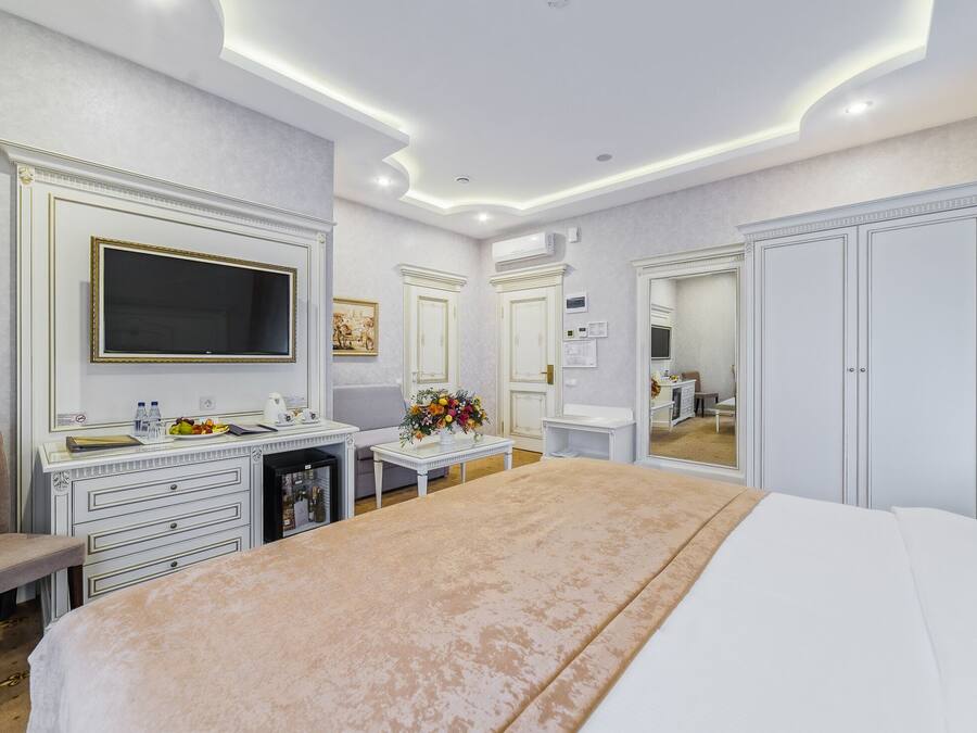 Quarto de hotel com uma cama grande, uma escrivaninha com televisão de tela plana, toucador com espelho e um guarda-roupa.