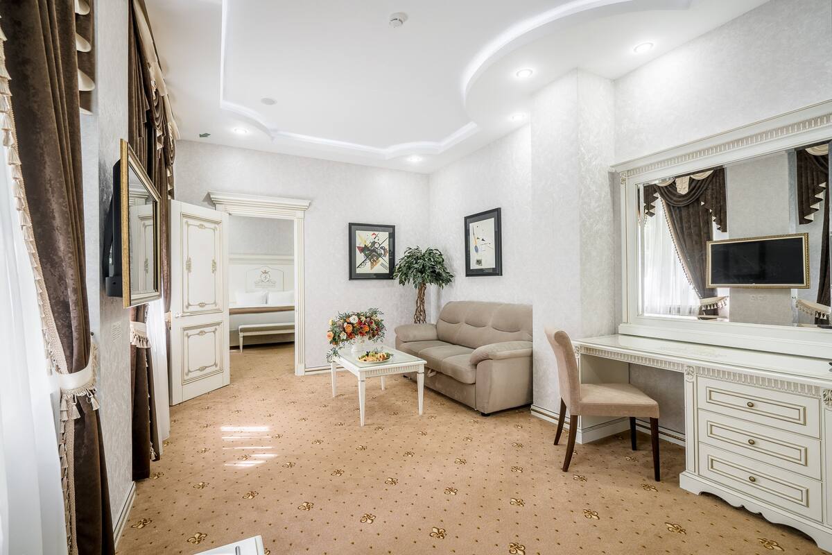 Une pièce avec une coiffeuse blanche, un canapé beige et une petite table sur laquelle est posé un vase de fleurs.