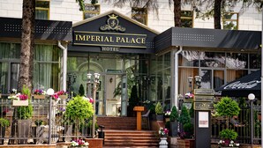 La façade de l’hôtel Imperial Palace, avec son entrée monumentale, son auvent arborant le logo Coca-Cola et ses panneaux de signalisation.