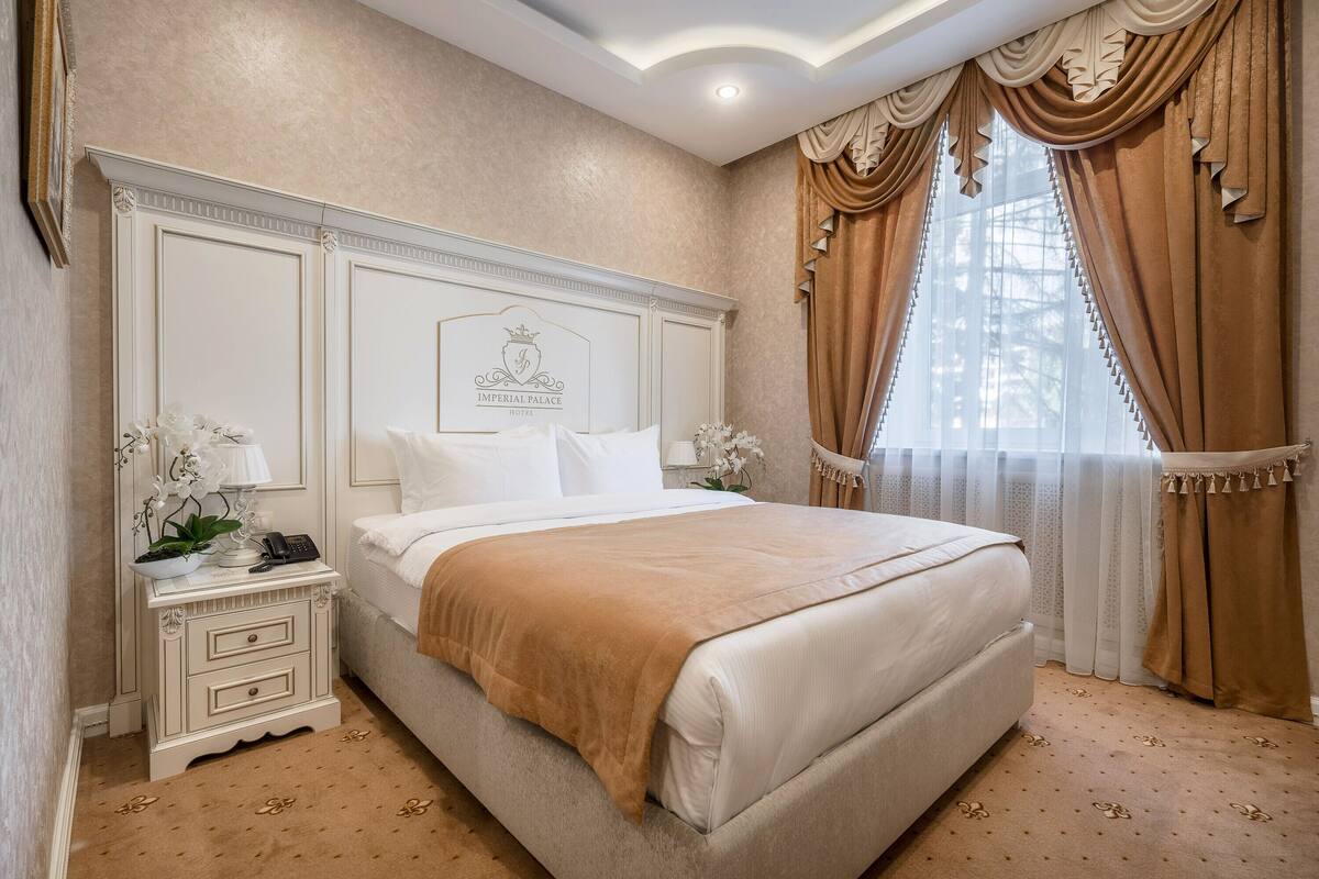 Une chambre à coucher avec un grand lit, une table de chevet avec une lampe et une tête de lit décorative.