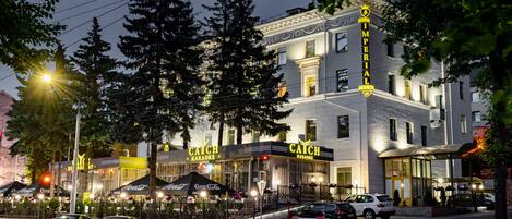 A building with "Imperial" signage, a "Catch Karaoke" sign, and outdoor seating with umbrellas.