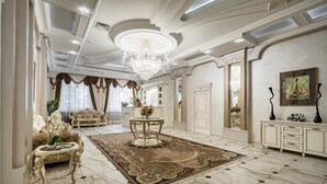 Un salon luxueux doté d’un sol en marbre, de meubles richement décorés et d’un grand lustre.