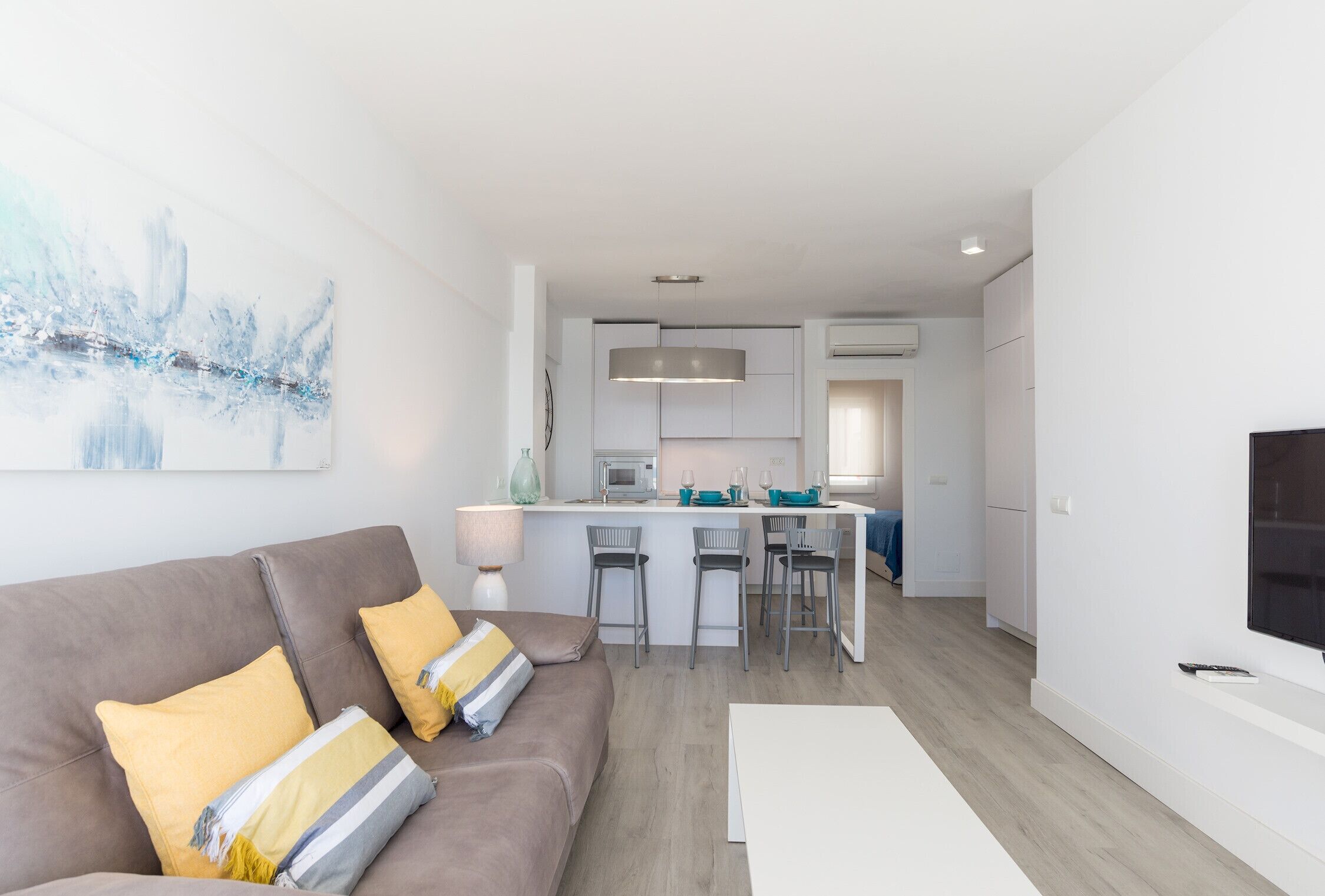 En moderne stue med sofa, et køkken og et spiseområde.