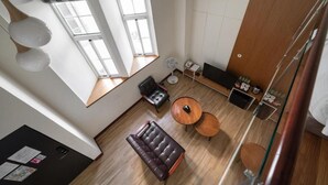 A modern room with a sofa, two round tables, a black leather chair, a wooden cabinet, and a large window providing natural light. - Anping Kensington Hotel (Tainan)