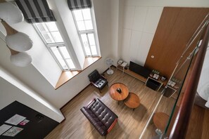 A modern room with a sofa, two round tables, a black leather chair, a wooden cabinet, and a large window providing natural light. - Anping Kensington Hotel (Tainan)