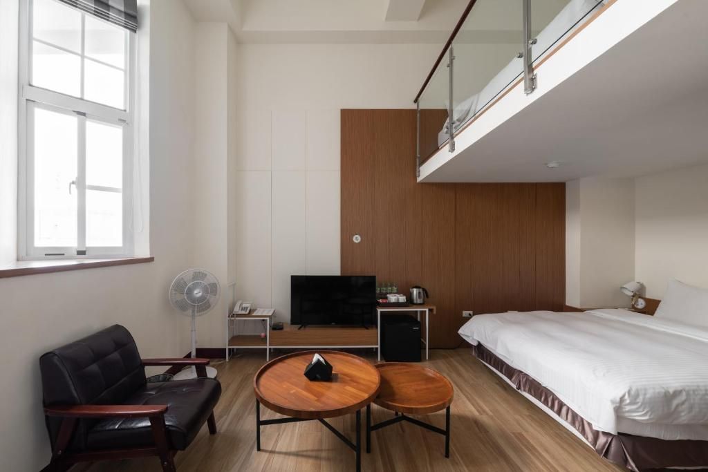 Et hotelværelse med seng, skrivebord, stol, fjernsyn og ventilator.