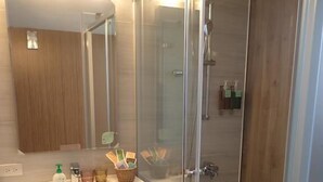 Ein modernes Badezimmer mit einer Duschkabine aus Glas, einem Holzbadezimmer-Möbel und einem Schachbrettfußboden.