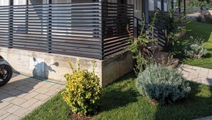 Ein modernes, mehrgeschossiges Wohngebäude mit überdachter Außenanlage, befestigter Auffahrt und gepflegter Bepflanzung.