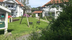 A residential area with houses, a swing set, and a small playhouse.