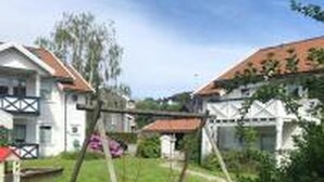 A residential area with houses, a swing set, and a lawn.