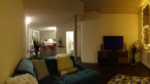 A living room with a blue sofa, a television, and a patterned rug. - Harun Apartment (Interlaken)