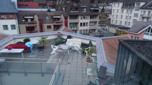 A rooftop terrace with outdoor furniture, a small table, and potted plants. - Harun Apartment (Interlaken)