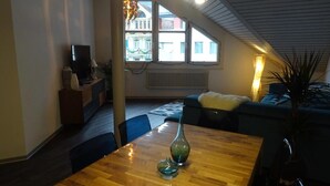 A cozy living room with a wooden dining table, a sofa, and a TV. - Harun Apartment (Interlaken)
